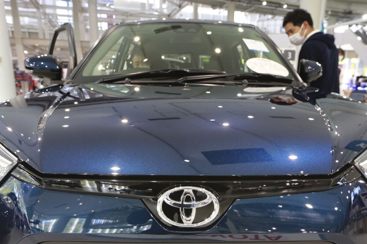 A man checks a car at a Toyota show room in Tokyo on Oct. 18, 2021. Toyota’s profit for the fiscal third quarter slipped nearly 6%, the Japanese automaker said Wednesday, Feb. 9, 2022, highlighting the headwinds the world’s automakers are battling in a computer-chips crunch caused by the coronavirus pandemic. (AP Photo/Koji Sasahara)