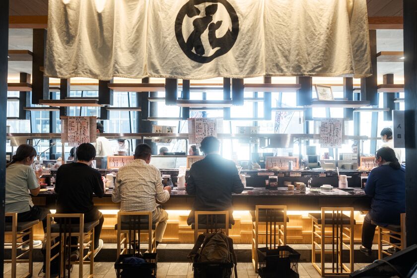 Customers eating at Hanamaru Ginza, a conveyor belt sushi restaurant in Japan.