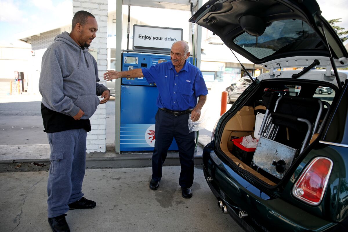 Two men at a gas station next to a car