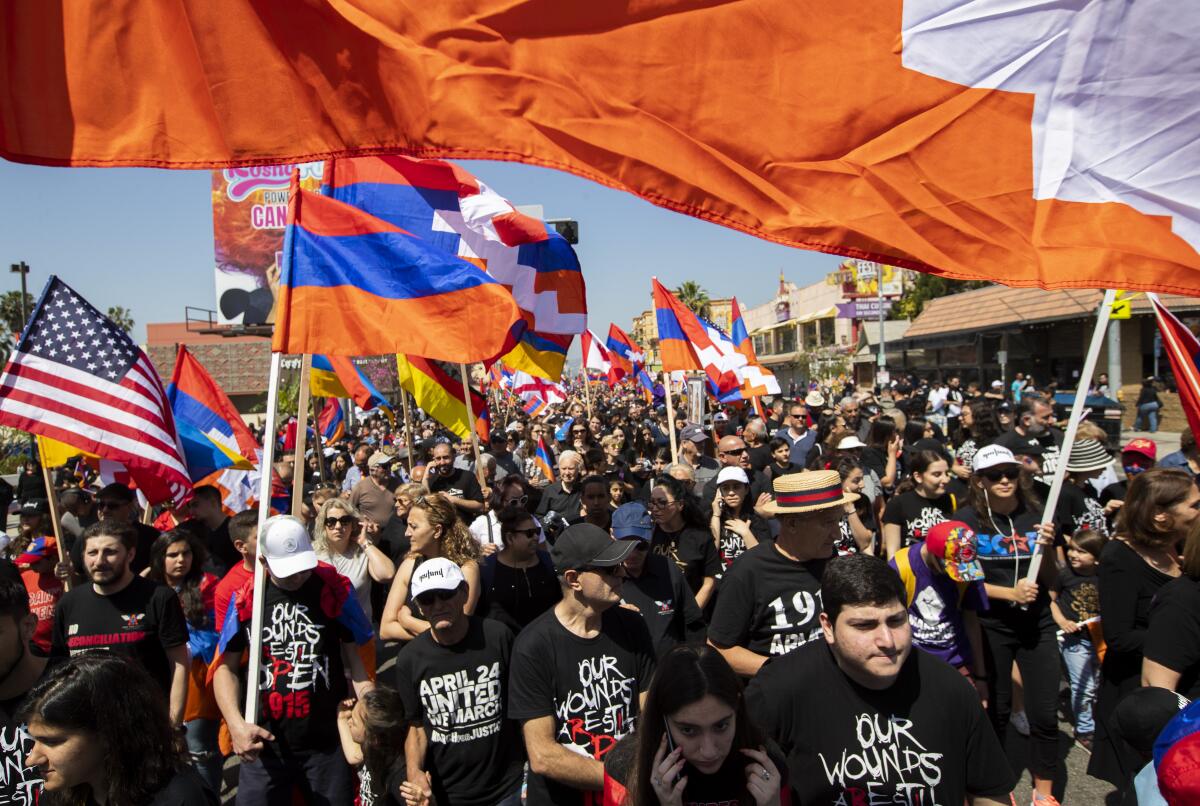 Large crowd of people marching with Armenian flags.