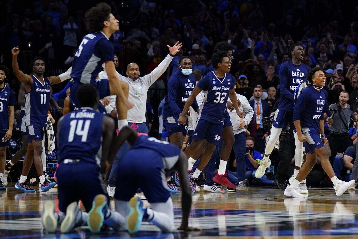 Saint Peter's players and coach Shaheen Holloway, middle back, celebrate a 67-64 victory over Purdue on March 25, 2022.