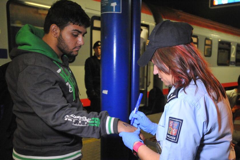 A Czech police officer marks a refugee with a number at the railway station in Breclav. (Igor Zehl / Associated Press)