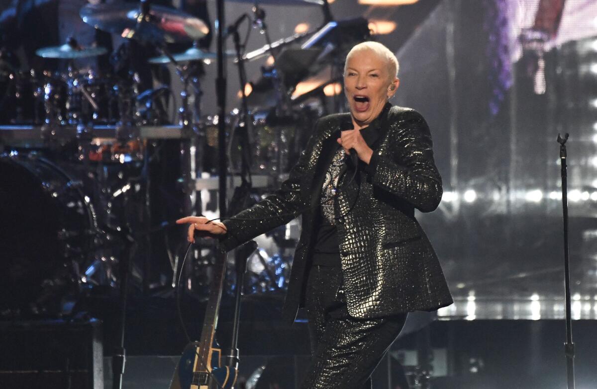 A female singer in a snakeskin suit performs onstage