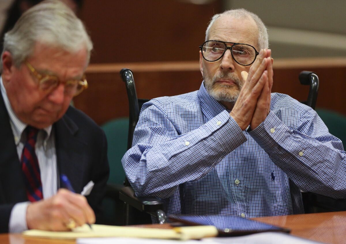 Robert Durst holds his hands together at a table next to his lawyer in a courtroom
