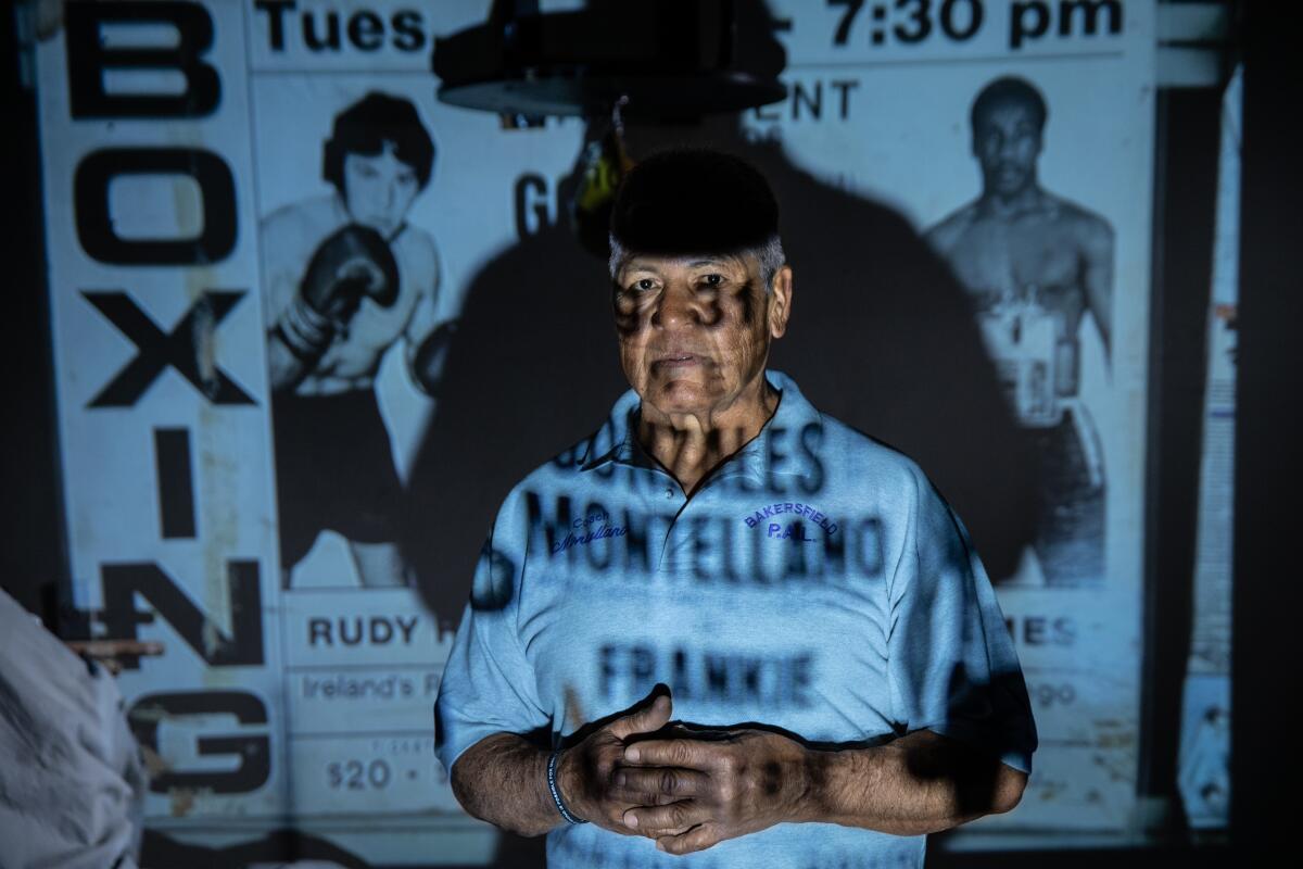 A man stands in front of a screen on which an old boxing poster is projected.