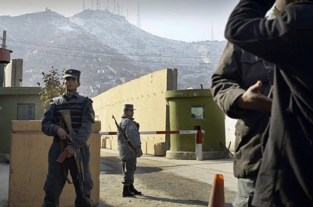 Afghan policemen stand guard outside of Kabul police headquarters, where an American advisor was killed Monday. An Afghan policewoman is suspected in the shooting.
