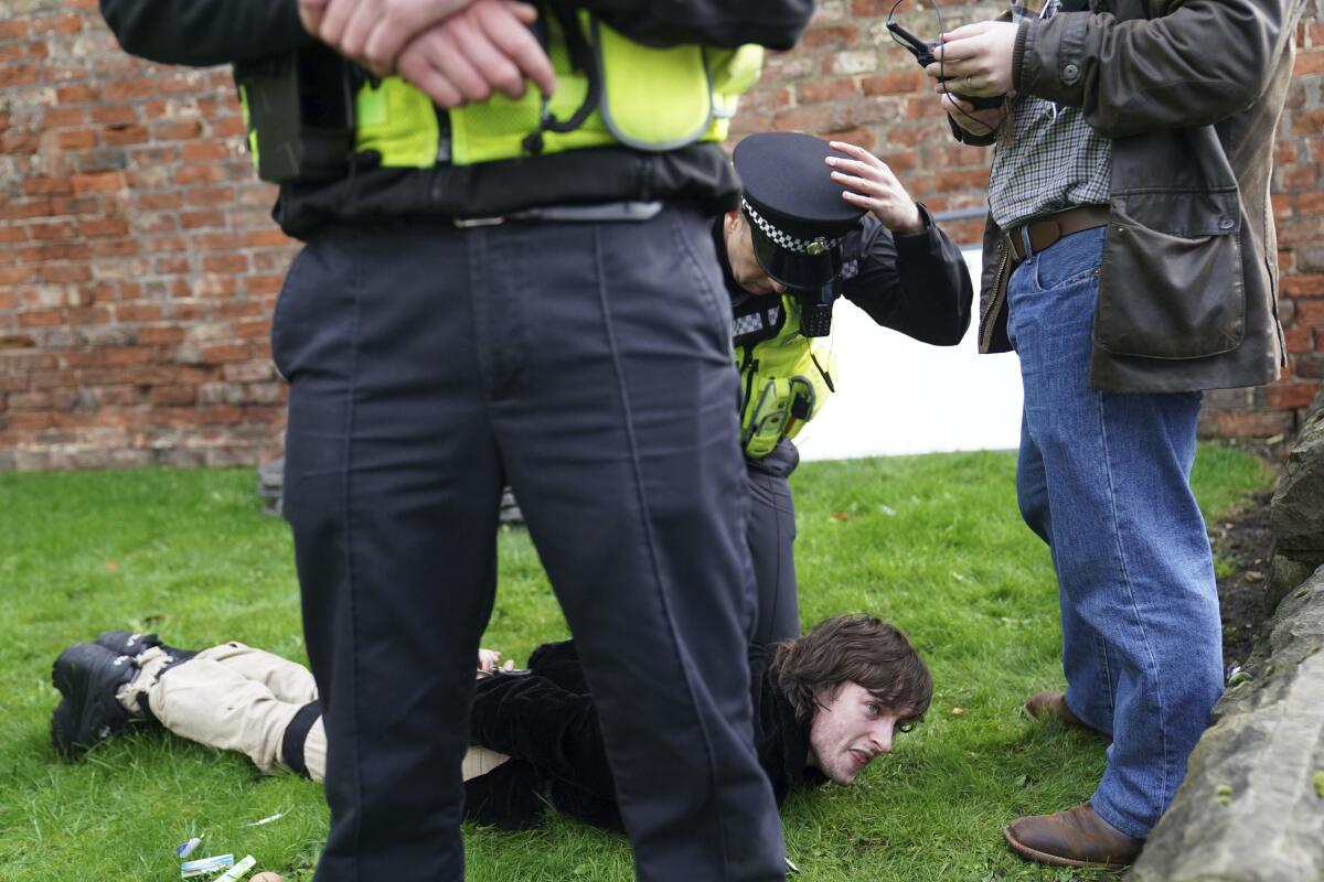 Detained protester on the ground surrounded by police