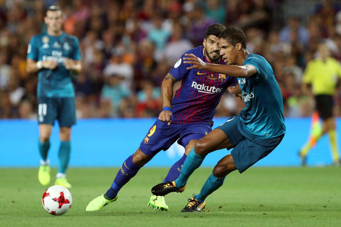 El delantero uruguayo del Barcelona Luis Suárez (i) disputa un balón con el central francés del Real Madrid Raphael Varane (d). EFE