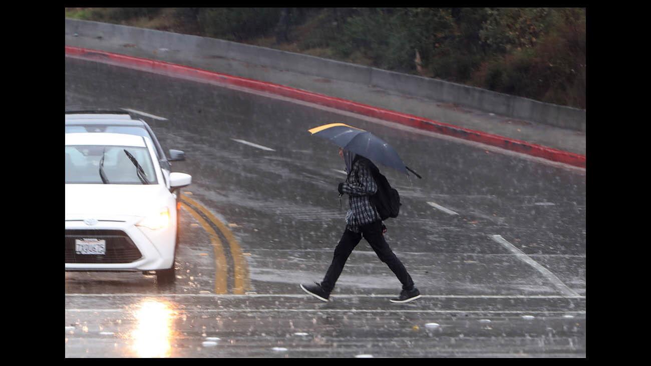 A person walks in heavy rain on Verdugo Road near Glendale Community College on Thursday, Dec. 6, 2018.