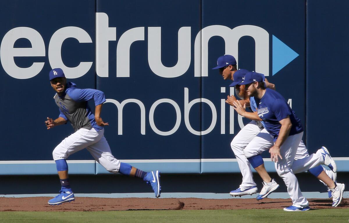 Dodgers right fielder Mookie Betts, left, runs through team drills during practice at Dodger Stadium.
