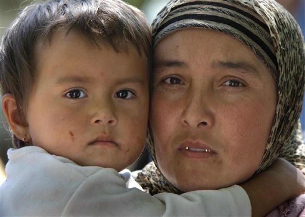 An ethnic Uzbek woman, no name given, holds her daughter as they stand near the Uzbek-Kyrgyz border in outskirts the southern city of Osh, Friday, June 18, 2010. The United Nations said as many as 1 million people may need aid in Kyrgyzstan and Uzbekistan, including the potential number of refugees, internally displaced, host families and others that may suffer in one way or another from the unrest. (AP Photo/Sergei Grits)