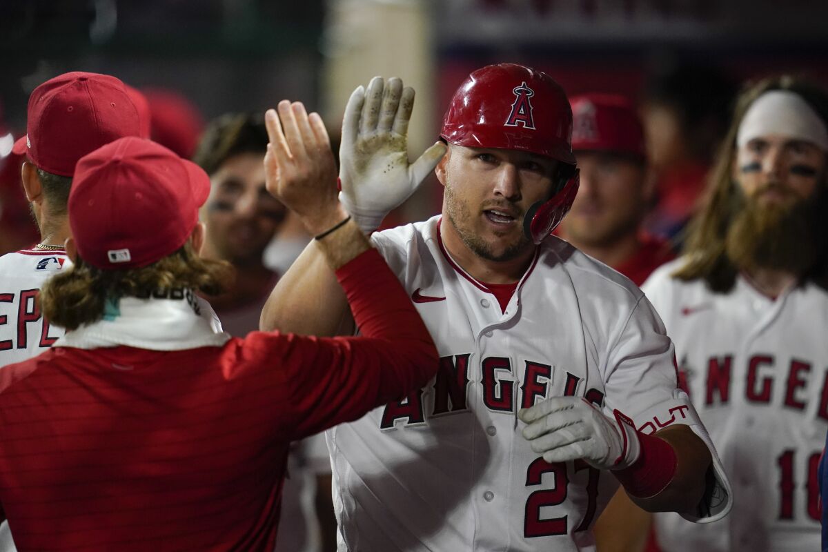 Los Angeles Angels center fielder Mike Trout (27) celebrates in the dugout after hitting a homerun during the seventh inning of a baseball game against the Houston Astros in Anaheim, Calif., Saturday, April 9, 2022. (AP Photo/Ashley Landis)