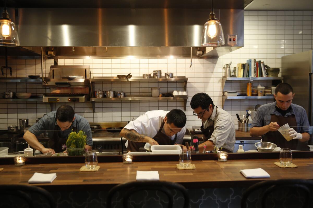 Chef Carlos Salgado, second from right, prepares dishes with his staff at Taco Maria in Costa Mesa on April 26, 2014.