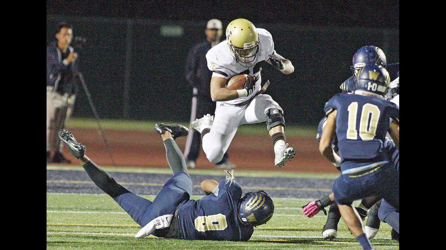 St. Francis' Areg Nazarian jumps over Warren's Darnay Harris in a CIF Southern Section first round football game at Warren High School in Downey on Friday, November 13, 2015.