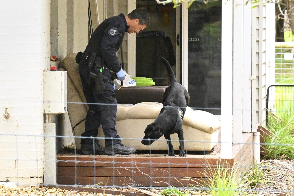 Police officer and dog investigating a property in Australia