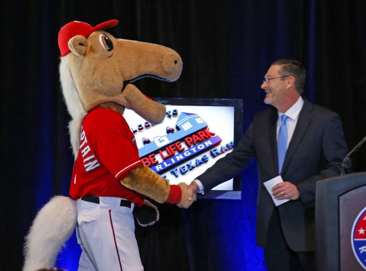 Bill Leavell, president of Globe Life Insurance, shakes hands with the Texas Rangers mascot, Captain, during a news conference to announce that they reached a naming-rights deal for the Rangers ballpark.