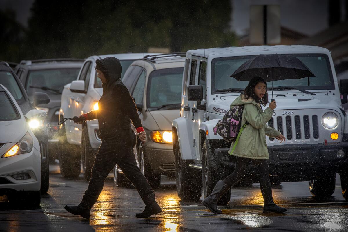 Parents take their children to school in the rain.