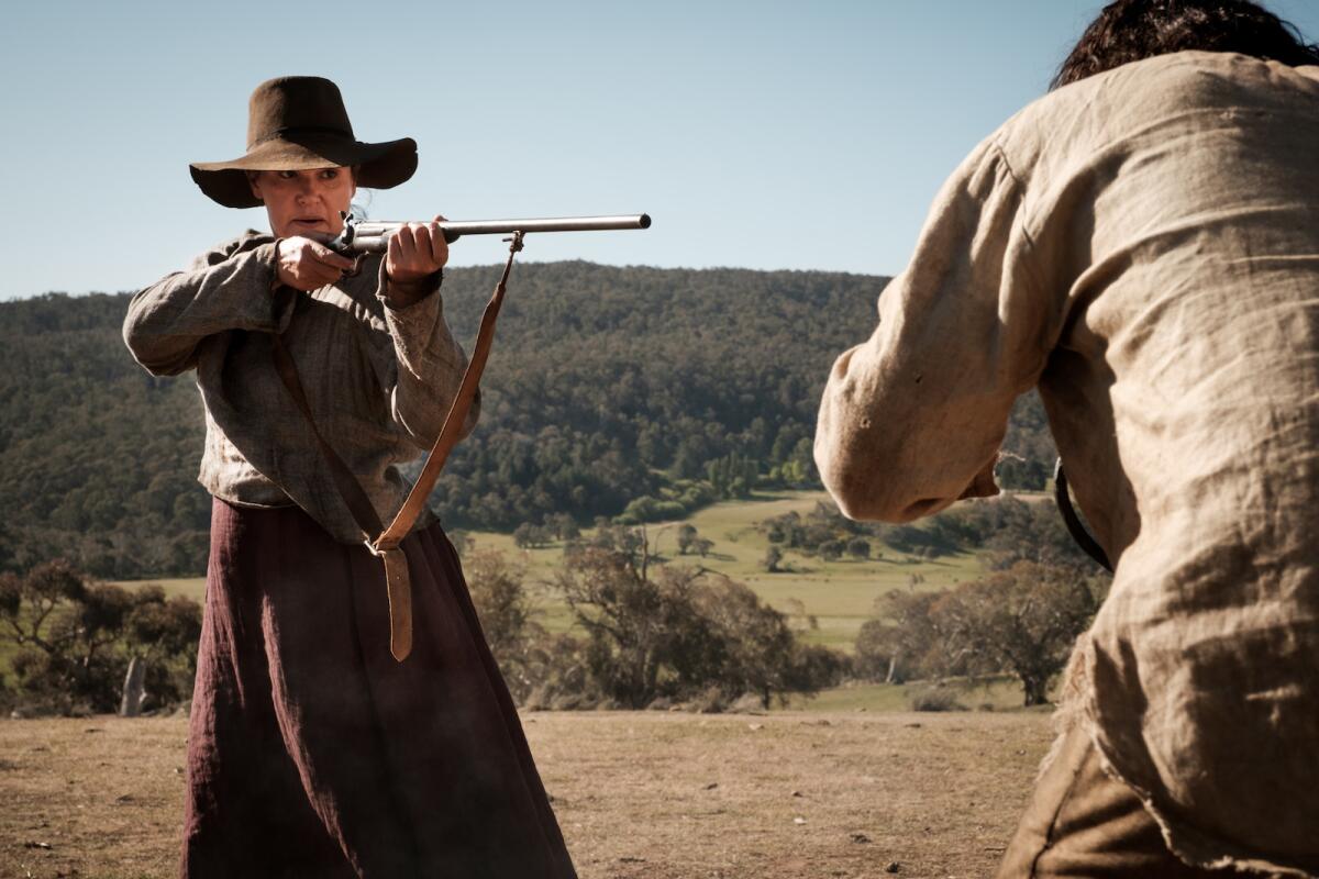 A woman in western apparel points a gun at a man in the movie "The Legend of Molly Johnson."
