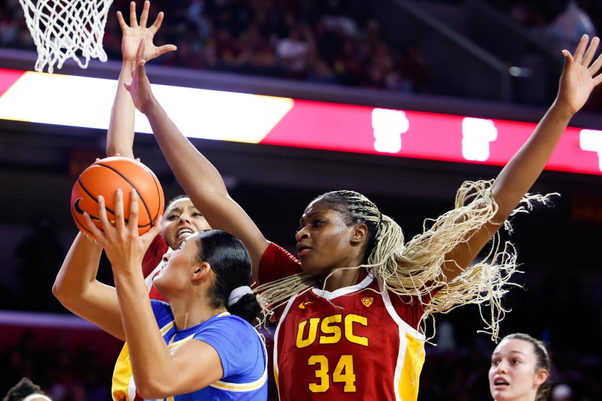 UCLA center Lauren Betts, center, tries to put up a shot in front of USC's JuJu Watkins, left, and Clarice Akunwafo.