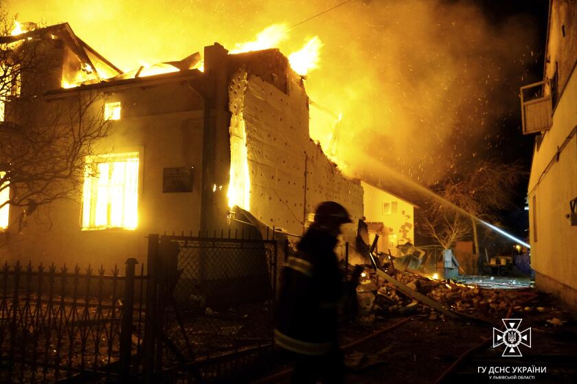 In this photo provided by the Ukrainian Emergency Service, firefighters work on the site of a burning building after a Russian drone attack in Dublyany, Lviv region, Ukraine, Monday, Jan. 1, 2024. (Ukrainian Emergency Service via AP)