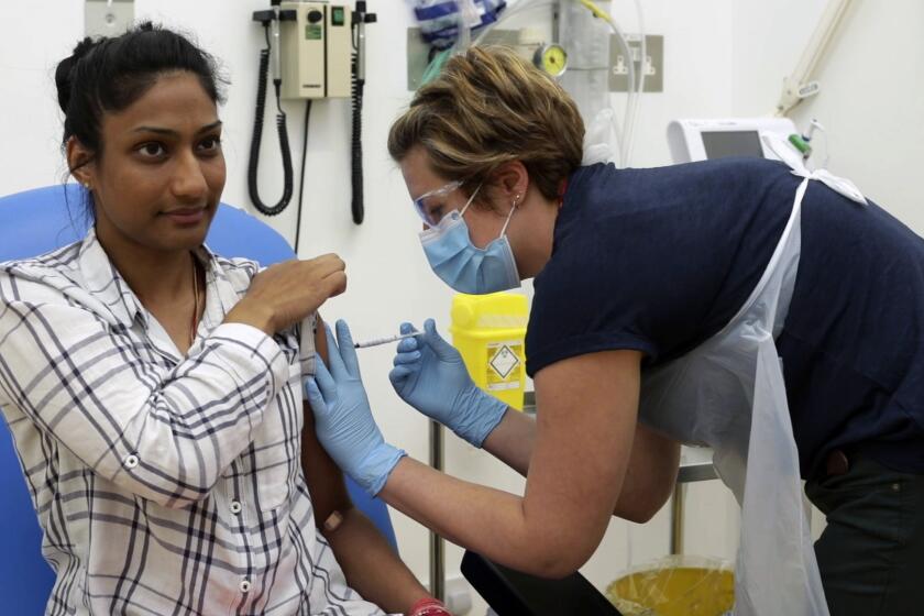 A clinical trial participant in England is injected with either an experimental COVID-19 vaccine or a placebo shot. Trials like this are underway around the world.