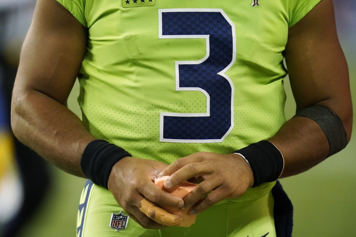 Seattle Seahawks quarterback Russell Wilson holds a sponge near his taped injured finger during the fourth quarter of an NFL football game against the Los Angeles Rams, Thursday, Oct. 7, 2021, in Seattle. Wilson left the game after the injury and the Rams won 26-17. (AP Photo/Elaine Thompson)
