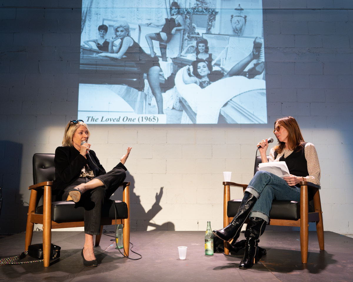 Two women have a conversation in front of an audience.