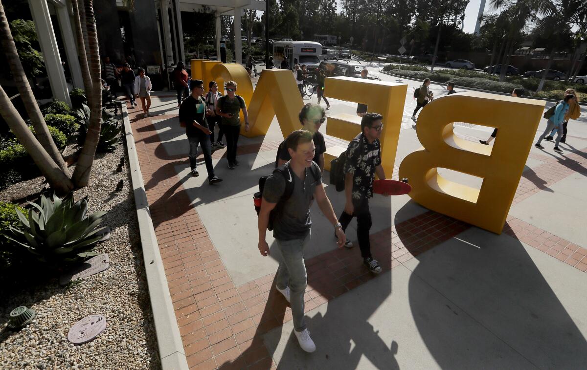 Students walk near a Cal State Long Beach sign.