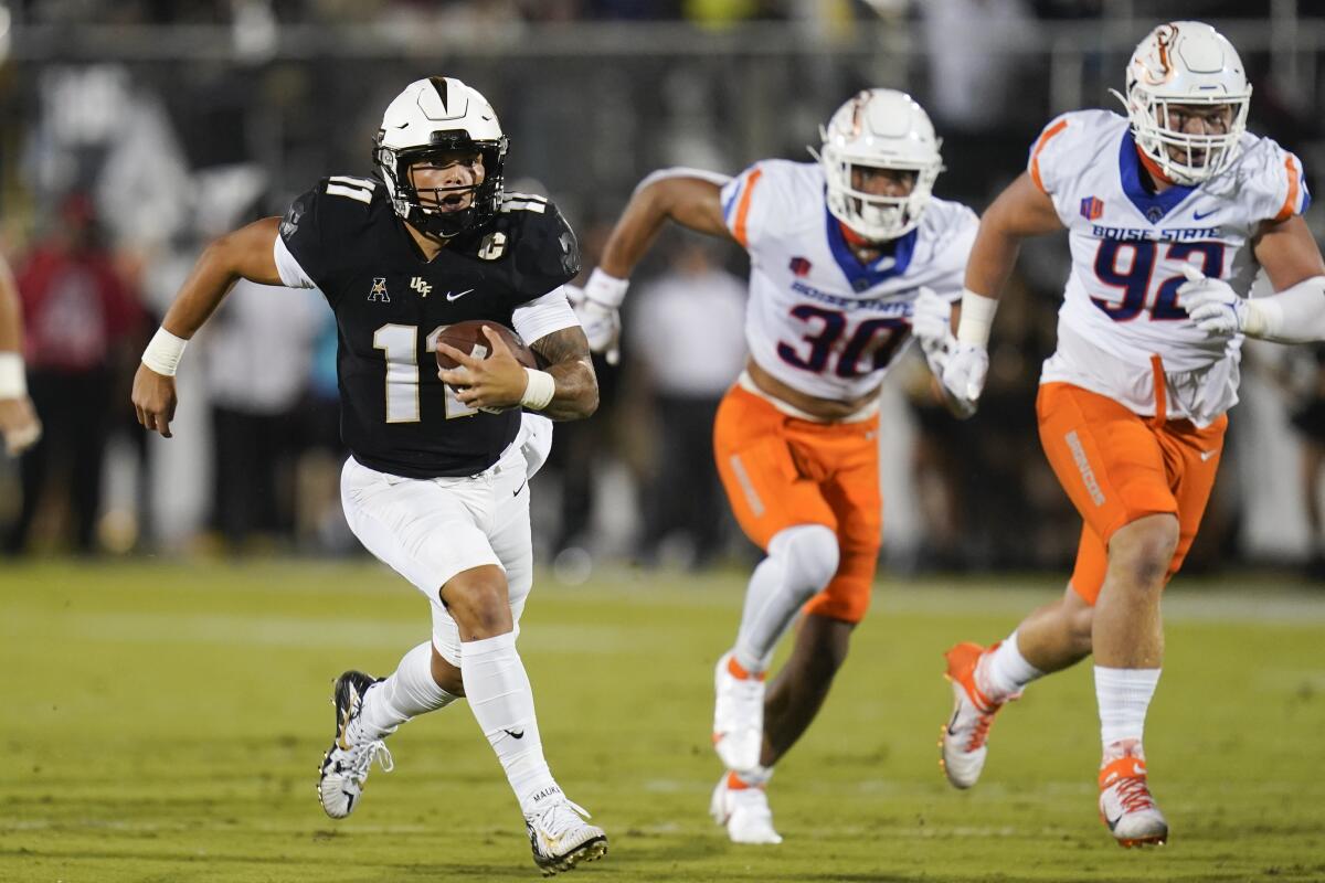Central Florida quarterback Dillon Gabriel, left, runs for yardage past Boise State defensive end Isaiah Bagnah (30) and defensive tackle Michael Callahan (92) during the first half of an NCAA college football game Thursday, Sept. 2, 2021, in Orlando, Fla. (AP Photo/John Raoux)