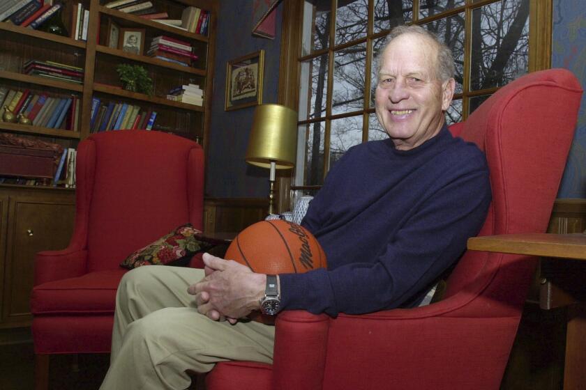 FILE - Frank Selvy poses with a basketball that belongs to his son, Mike, at his home Thursday, Feb. 5, 2004, in Simpsonville, S.C. Selvy, an All-America guard at Furman who scored an NCAA Division I-record 100 points in a game and later played nine NBA seasons, died Tuesday, Aug. 13, 2024. (AP Photo/Mary Ann Chastain, File)