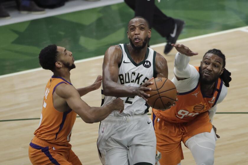 Milwaukee Bucks forward Khris Middleton, center, drives to the basket between Phoenix Suns guard Cameron Payne, left, and forward Jae Crowder, right, during the second half of Game 4 of basketball's NBA Finals Wednesday, July 14, 2021, in Milwaukee. (AP Photo/Aaron Gash)