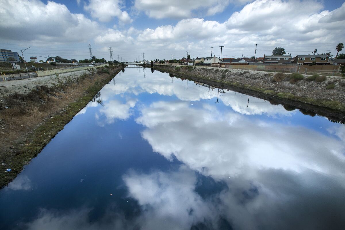 Clouds in a blue sky are reflected in a channel of water