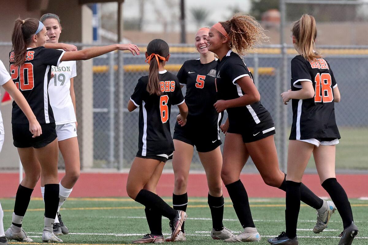 Huntington Beach's Sienna McAthy (5) is congratulated by teammates after scoring a goal against Edison.