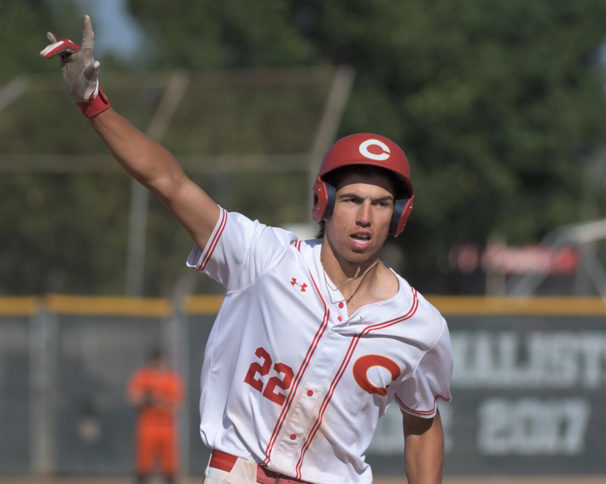 Corona High's Seth Hernandez gesturing as he circles the bases in a home jersey and batting helmet
