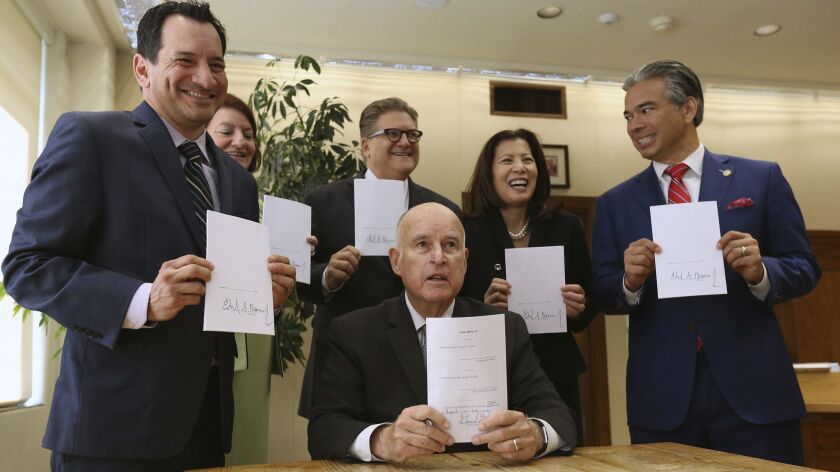Gov. Jerry Brown shows the bail bill he signed as other state officials hold copies: from left, Assembly Speaker Anthony Rendon, Senate President Pro Tem Toni Atkins, Sen. Bob Hertzberg, Supreme Court Chief Justice Tani Cantil-Sakauye and Assemblyman Rob Bonta.