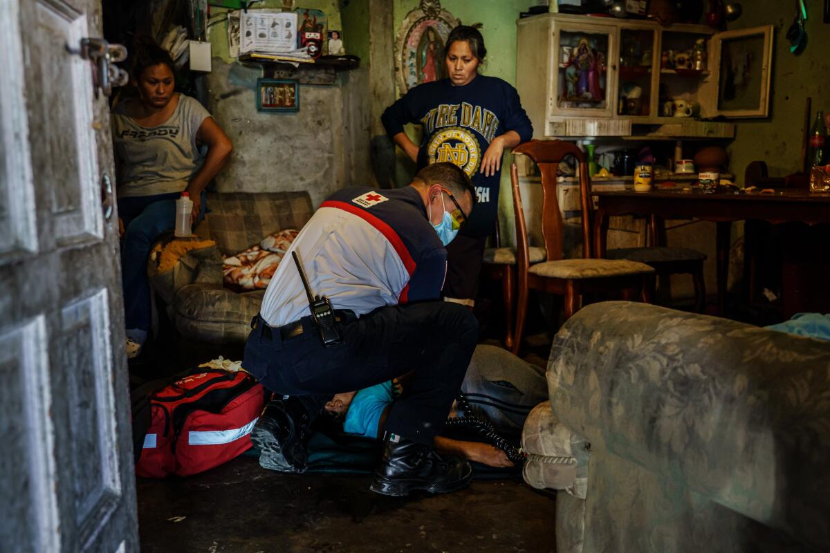 El paramédico de la Cruz Roja, Sergio García, toma el pulso mientras intenta resucitar a María Ruiz Olmedo, de 71 años, mientras los miembros de la familia observan en su casa de Tijuana en abril de 2020.
