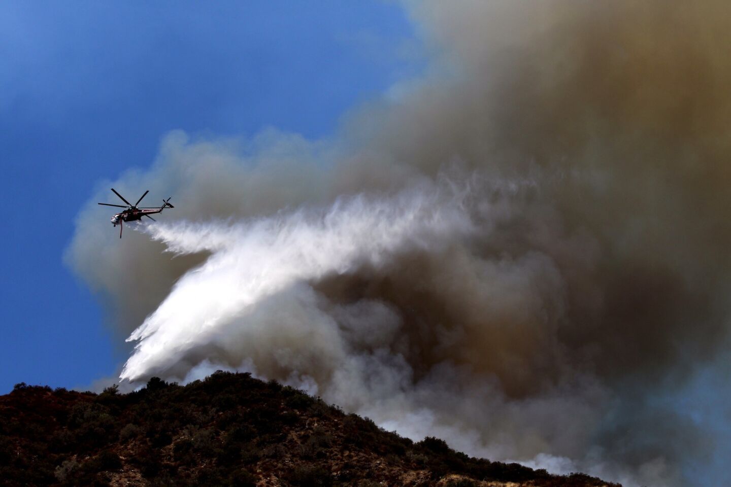 An Orange County Fire helicopter makes a water drop on a brush fire in Silverado Canyon.