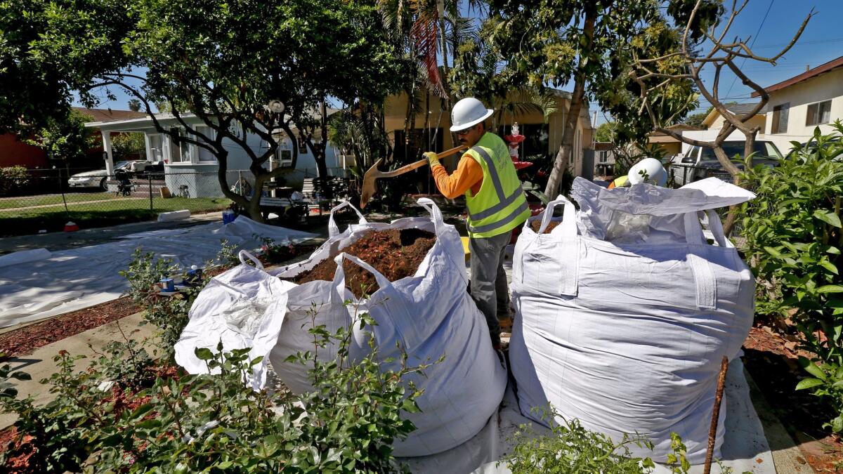 Workers remove soil from homes in Boyle Heights in 2015. State regulators have released a plan to clean 2,500 additional lead-contaminated properties over a two-year period.