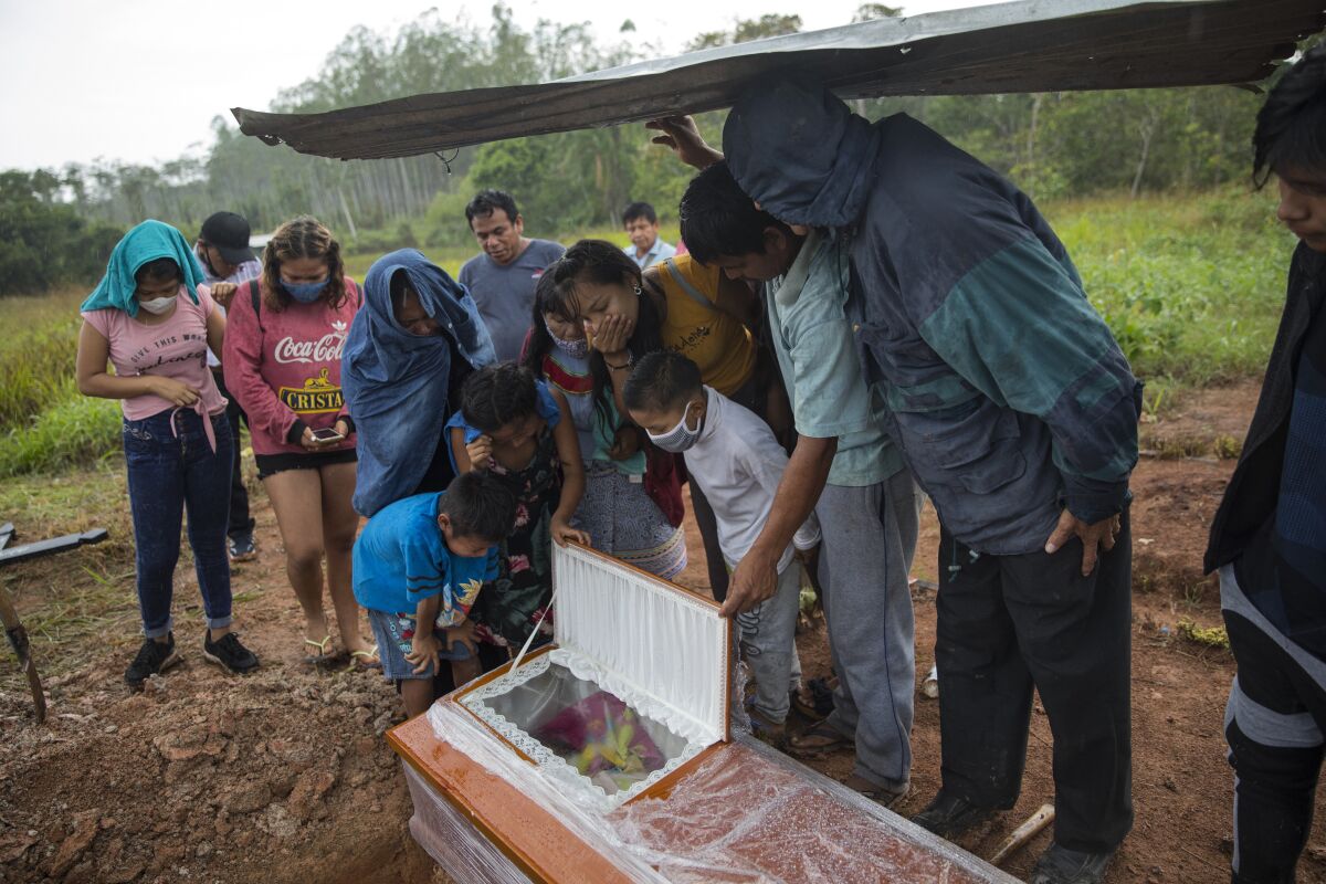 Family members look in the coffin that contains the remains of Manuela Chavez who died from symptoms related to the new coronavirus at the age of 88, during a burial service in the Shipibo Indigenous community of Pucallpa, in Peru's Ucayali region, Monday, Aug. 31, 2020. The Shipibo have tried to prevent COVID-19's entrance by blocking off roads and isolating themselves. (AP Photo/Rodrigo Abd)