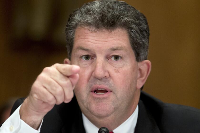 Postmaster General Patrick Donahoe gestures as he speaks on Capitol Hill.