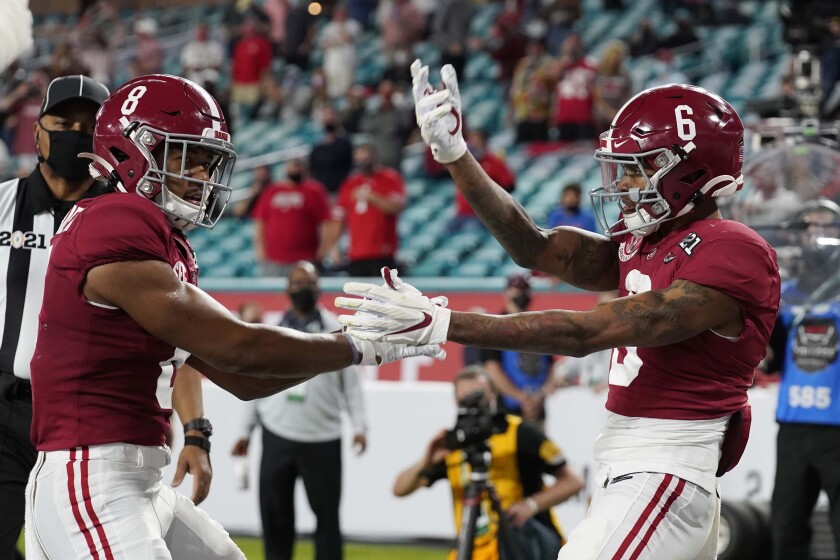 Alabama wide receiver John Metchie III, left, congratulates wide receiver DeVonta Smith, after Smith scored a touchdown against Ohio State during the first half of an NCAA College Football Playoff national championship game, Monday, Jan. 11, 2021, in Miami Gardens, Fla. (AP Photo/Chris O'Meara)