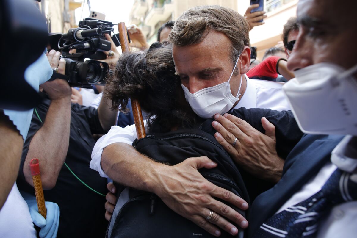 French President Emmanuel Macron hugs a resident as he visits a devastated street of Beirut, Lebanon, Thursday Aug.6, 2020. French President Emmanuel Macron has arrived in Beirut to offer French support to Lebanon after the deadly port blast.(AP Photo/Thibault Camus, Pool)