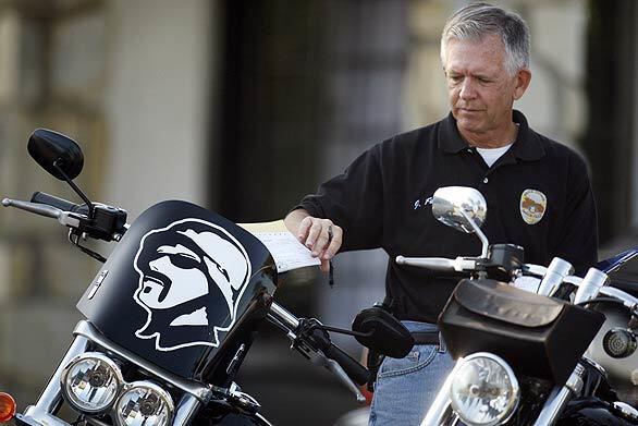 An Anaheim police officer tags one of the motorcycles being impounded after a raid was conducted on several homes in Anaheim occupied by the Set Free Christian motorcycle group.