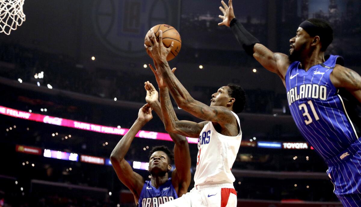 Clippers guard Lou Williams splits the defense of Magic forward Terrence Ross (31) and center Mo Bamba for a layup Sunday.