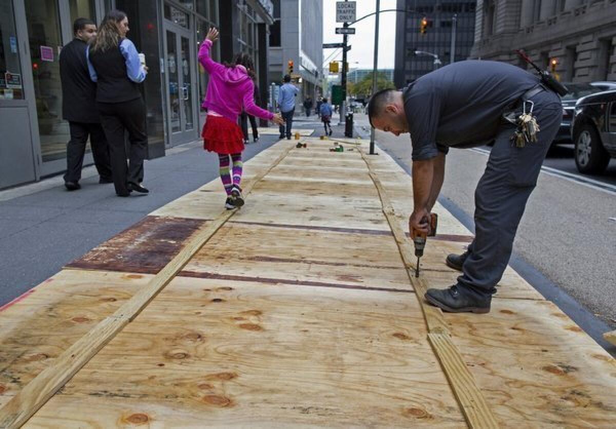 A worker puts plywood over sidewalk grates in Lower Manhattan as Wall Street prepares for Hurricane Sandy.