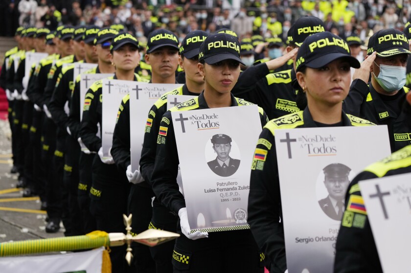 Unidades de la Policía Nacional de Colombia sostienen fotos de colegas que murieron 