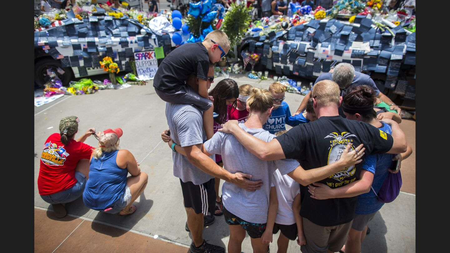 People pray in front of a growing memorial at the Dallas Police Headquarters.