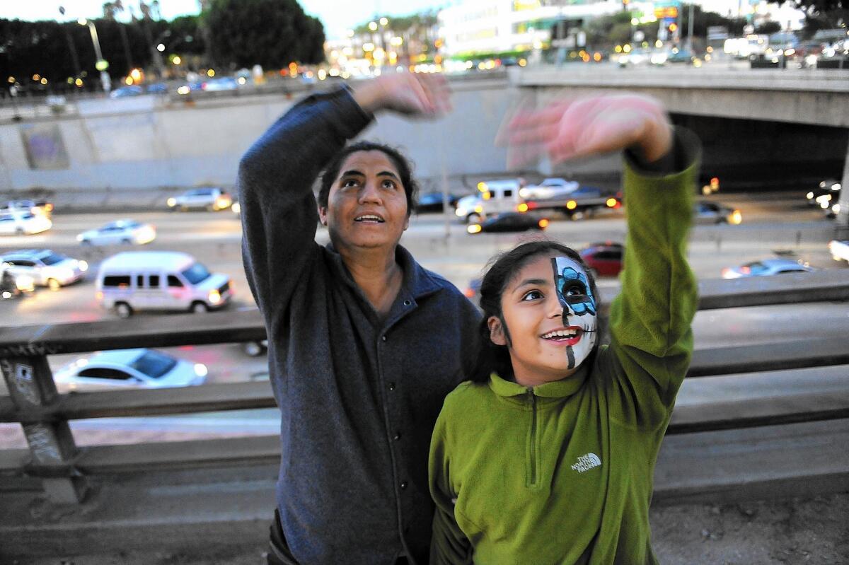 Lucia Sanchez, left, and her 9-year-old daughter Laura wave to inmates inside the Los Angeles Metropolitan Detention Center during the National Day Laborer Organizing Network's 4th Chant Down the Walls concert.