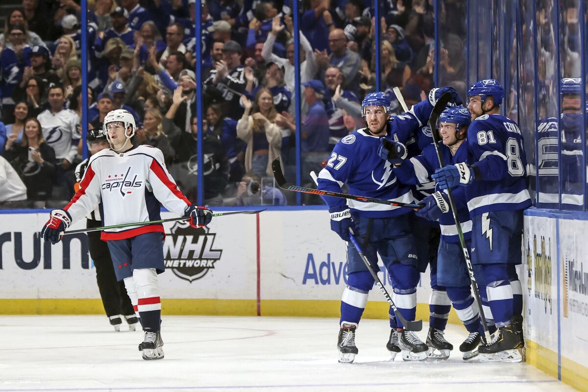 Tampa Bay Lightning's Brayden Point (21) celebrates his goal with Ryan McDonagh (27) and Erik Cernak (81) as Washington Capitals' Connor McMichael reacts during the third period of an NHL hockey game Monday, Nov. 1, 2021, in Tampa, Fla. The Lightning won 3-2. (AP Photo/Mike Carlson)