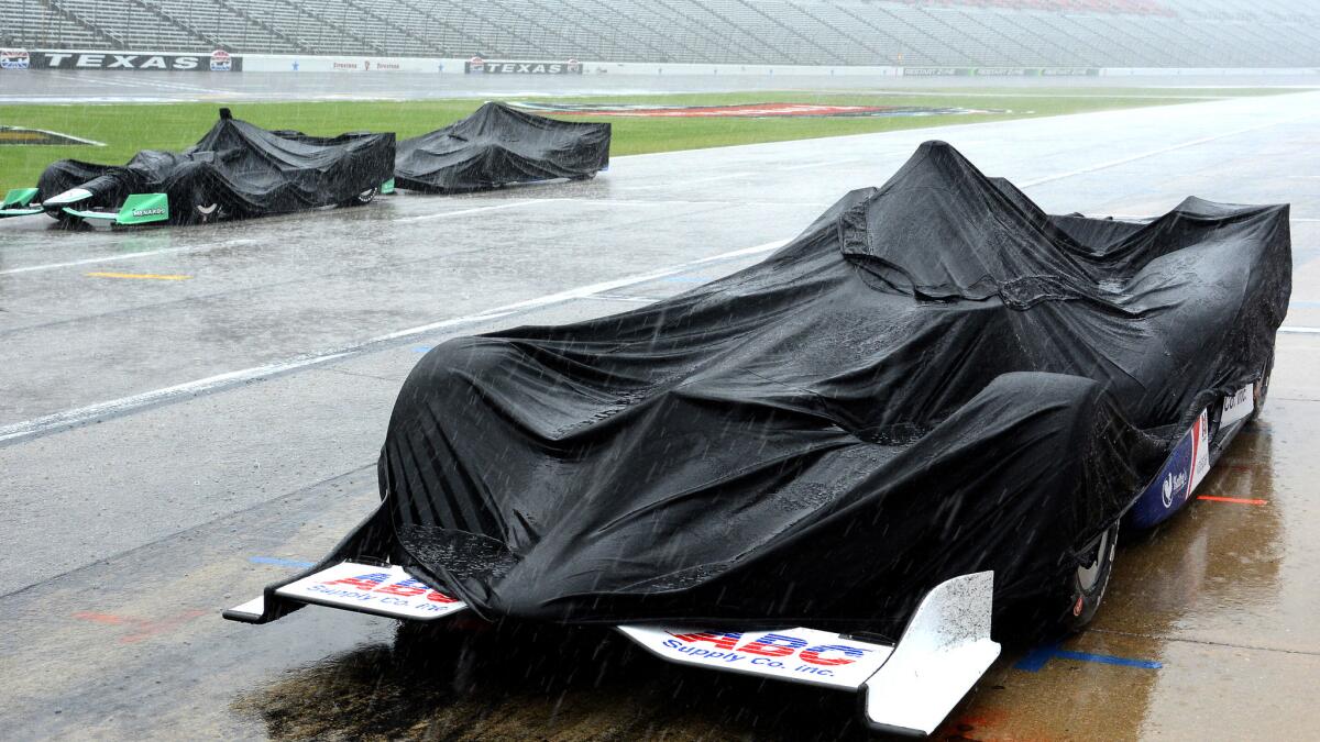 Race cars are covered during a thunderstom at Texas Motor Speedway on Sunday.